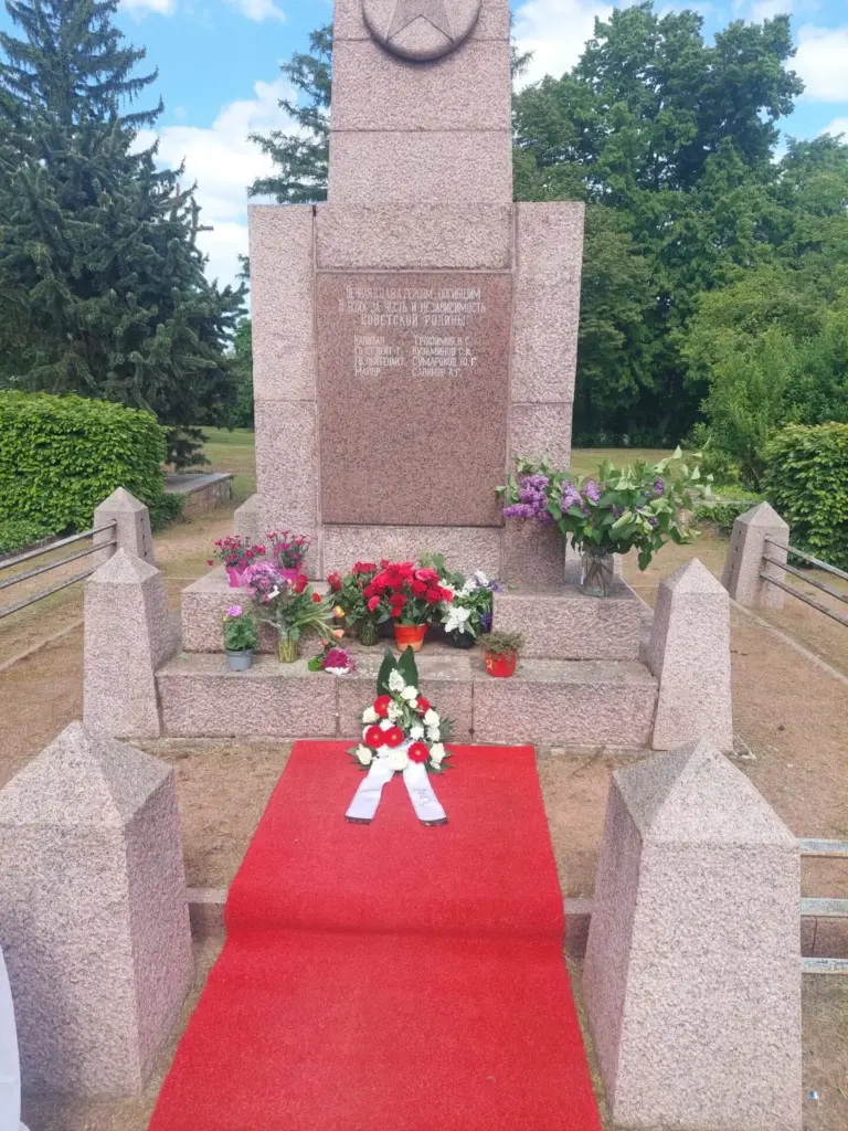 Tag der Befreiung vom Faschismus Sowjetisches Ehrenmal mit Blumen, davor ein Gesteck mit weißer Schleife auf einem roten Teppich