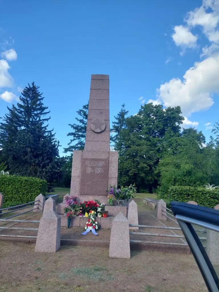 Tag der Befreiung vom Faschismus Obelisk eines sowjetischen Ehrenmals mit Stern, davor niedergelegte Blumen und ein Gesteck