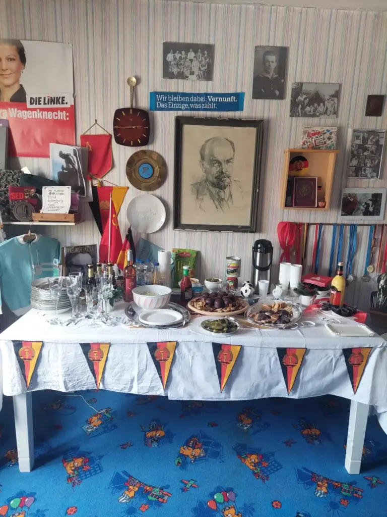 Feierlichkeiten zum Geburtstag der DDR Buffet im Haus Frieda mit Gebäck, Salzgurken und Getränken, an der Wand Bilder, Fahnen und Erinnerungsstücke