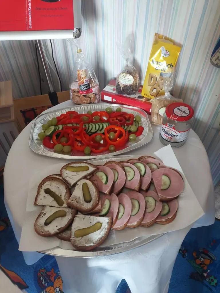 Feierlichkeiten zum Geburtstag der DDR Imbiss im Haus Frieda: belegte Brote, eine Platte mit Paprika, Gurke und Trauben, dazu Gebäck und Soljanka